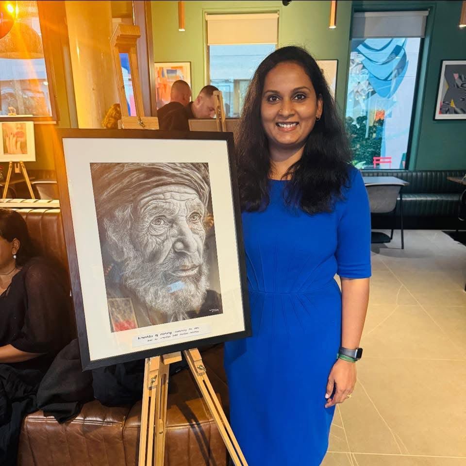 Lakshmi Sridhar with a framed portrait drawing at an exhibition